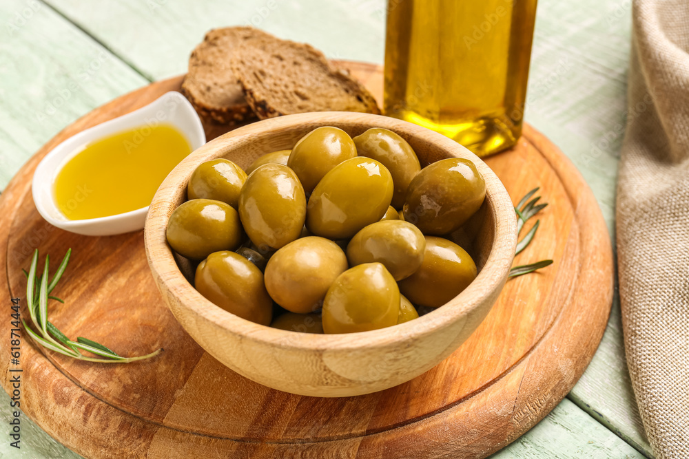 Bowl with ripe olives on green wooden background