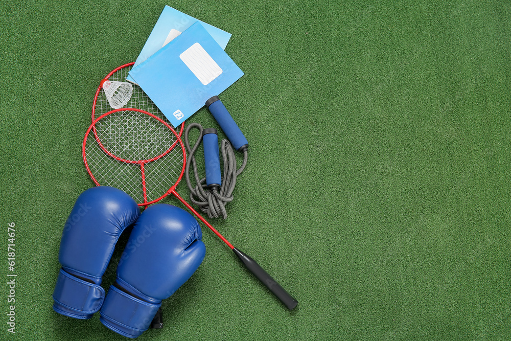 Notebooks with boxing gloves, badminton rackets and skipping rope on color background