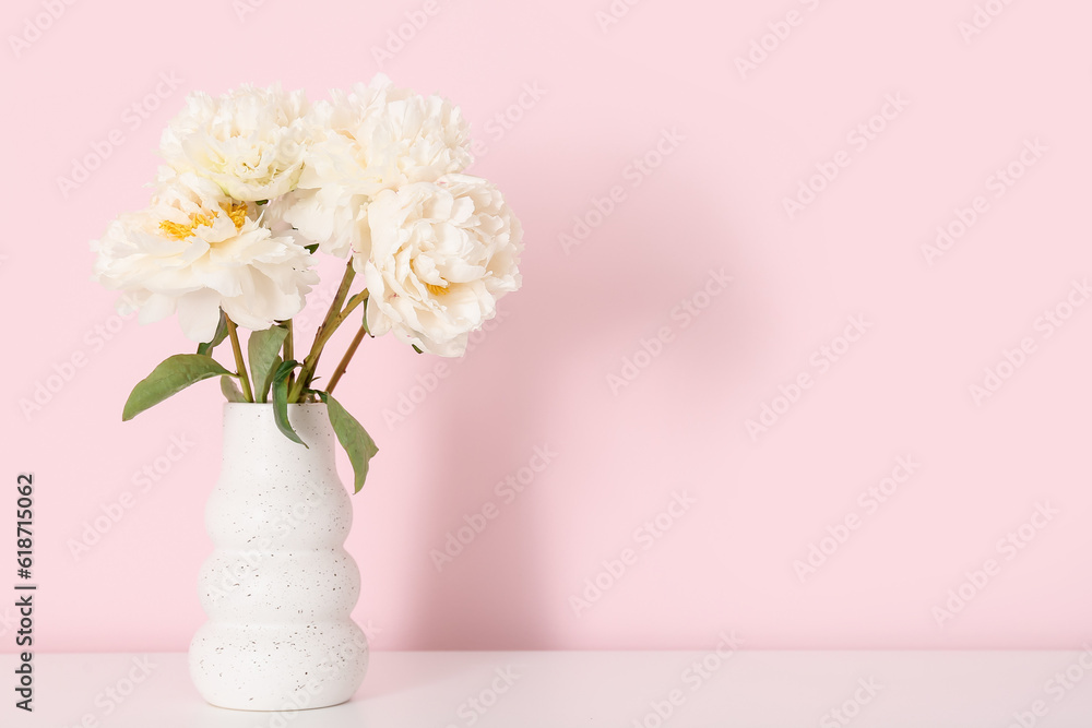 Vase of white peonies on dresser near pink wall