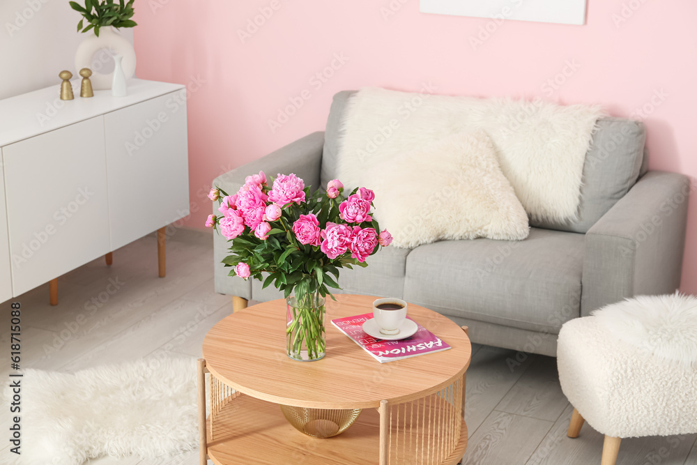 Vase of pink peonies on coffee table with couch in living room