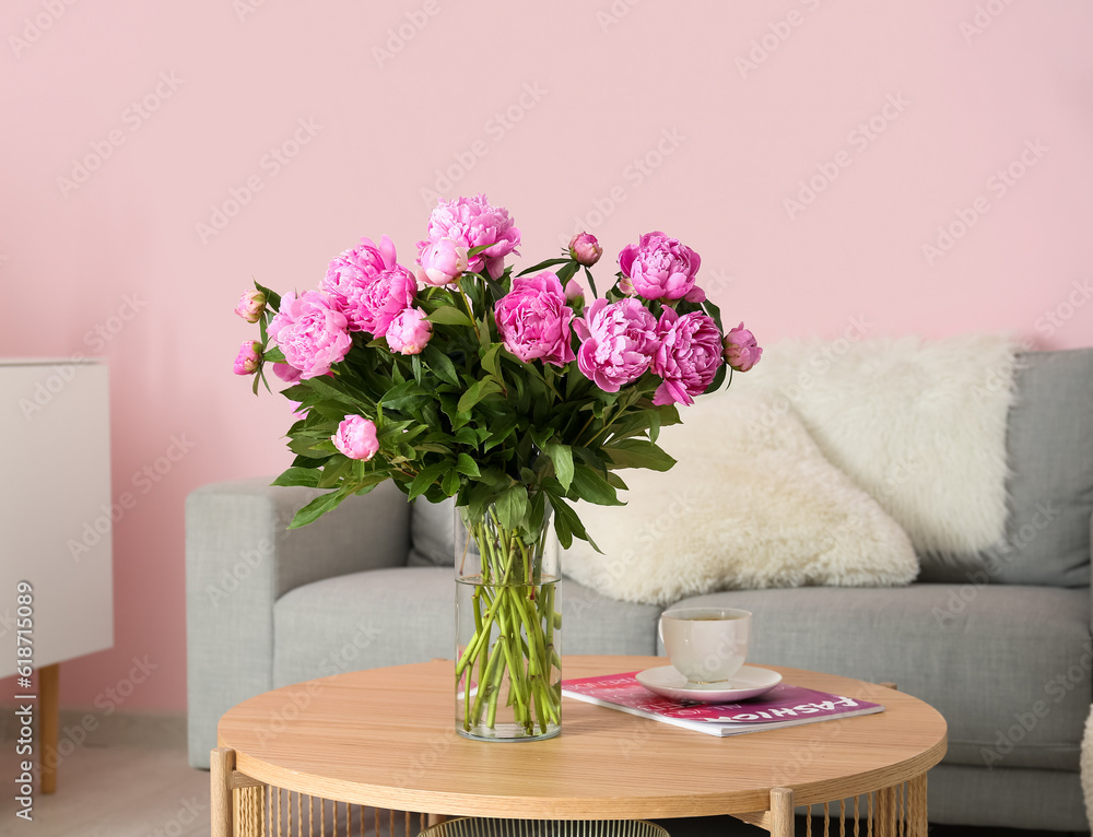 Vase of pink peonies on coffee table with couch in living room