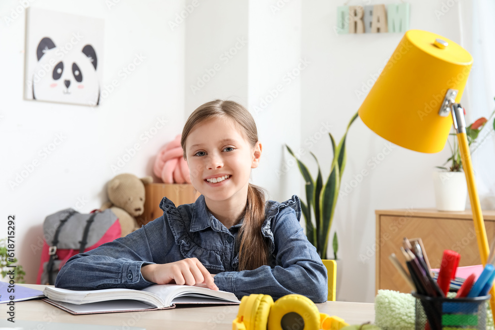 Little girl reading schoolbook at home