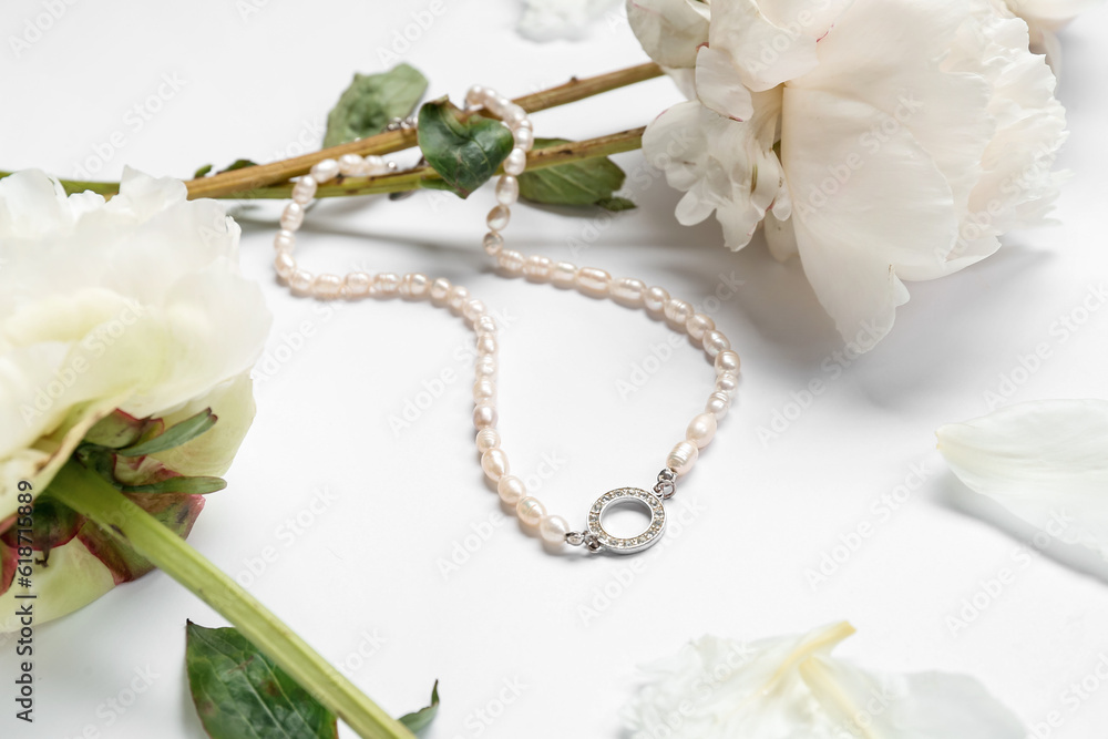 Composition with stylish female necklace and beautiful peony flowers on white background