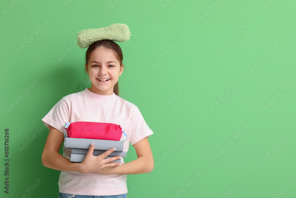 Little girl with pencil cases on green background