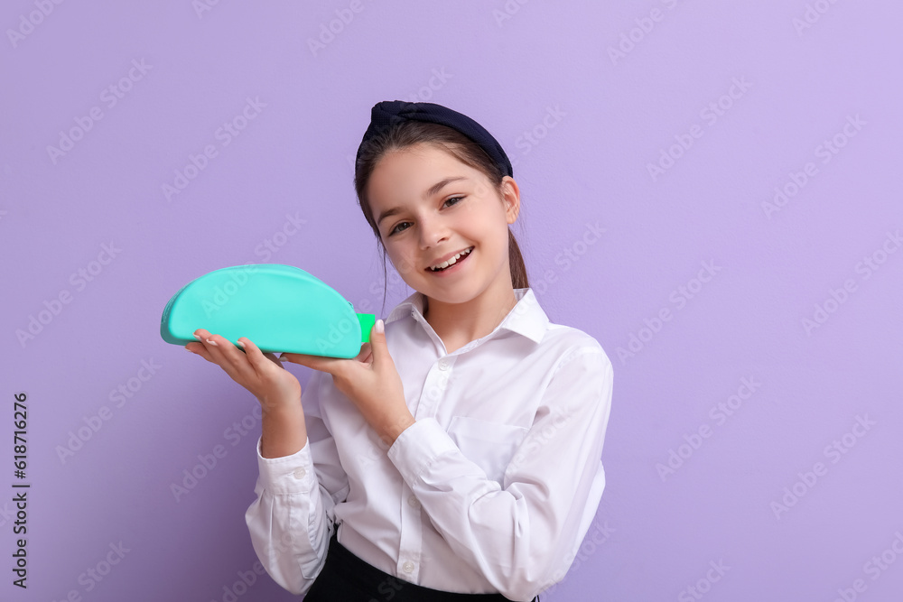 Little schoolgirl with pencil case on lilac background