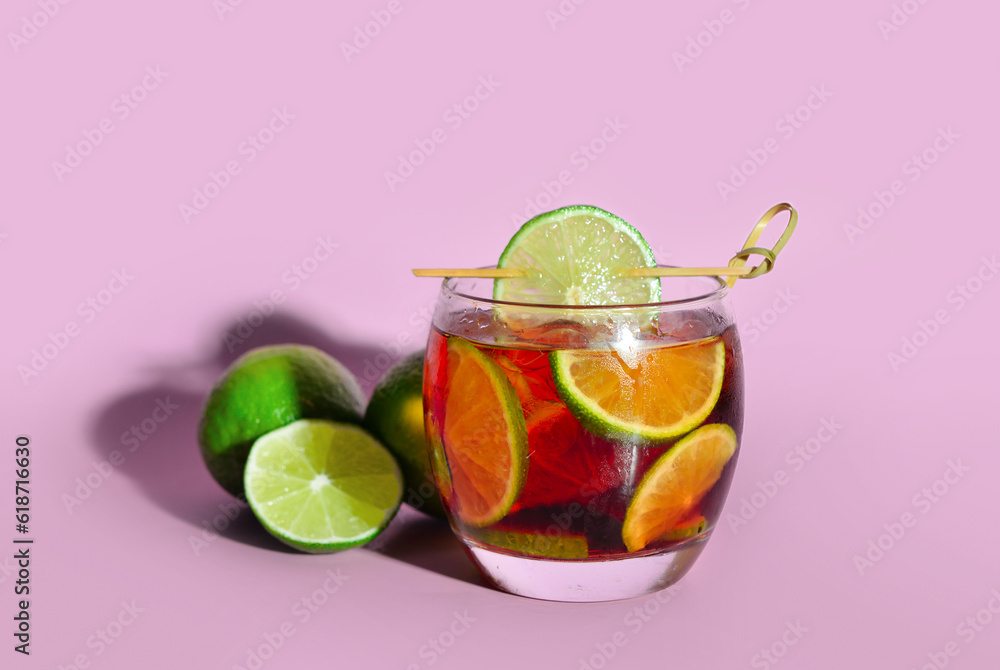 Glass of cold Cuba Libre cocktail on lilac background