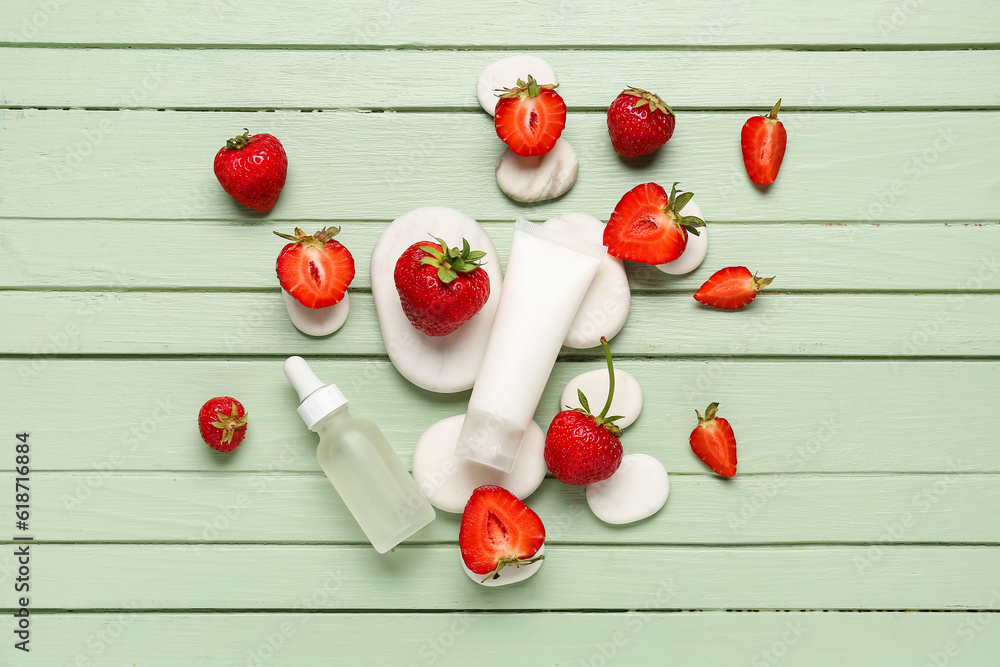 Different cosmetic products and strawberries on green wooden background