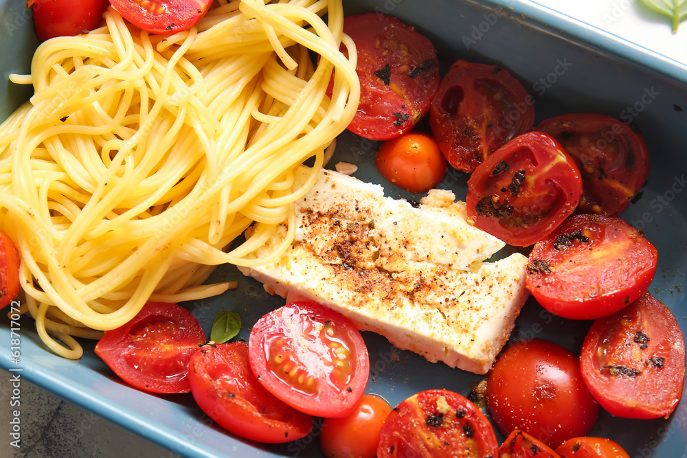 Baking dish of tasty pasta with tomatoes and feta cheese on table