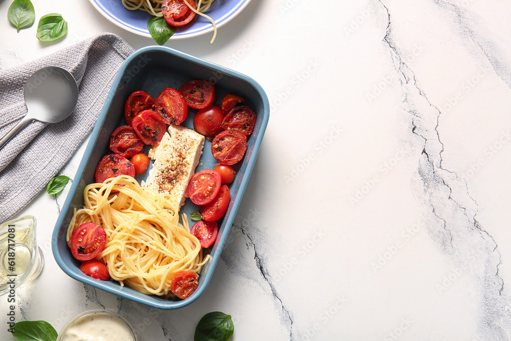 Baking dish of tasty pasta with tomatoes and feta cheese on white marble background