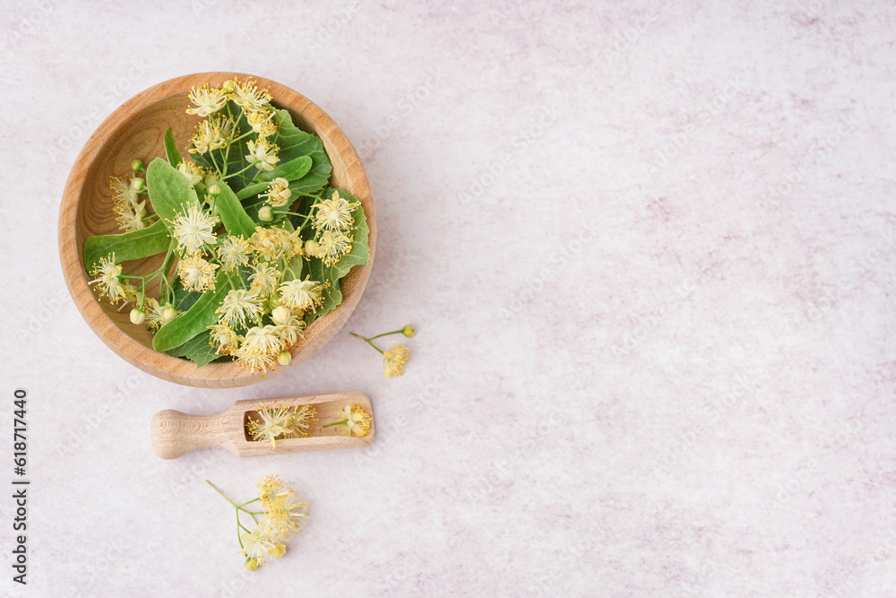 Wooden bowl with fresh linden flowers on light background