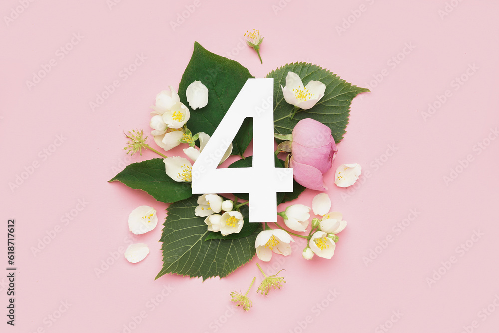 Green leaves and flowers with paper number four on pink background