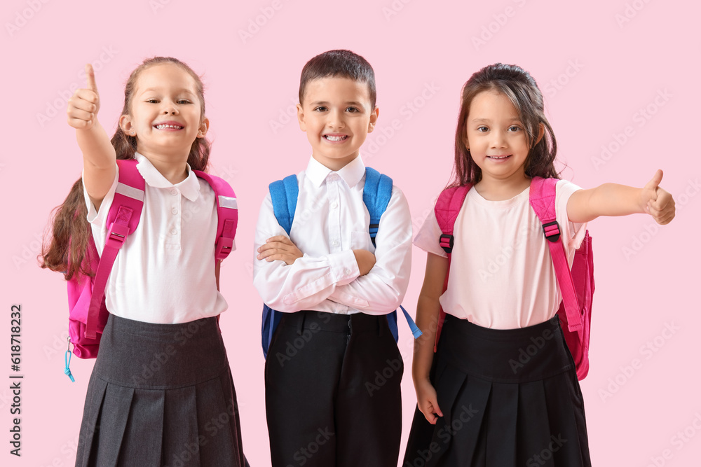 Little schoolchildren showing thumb-up on pink background