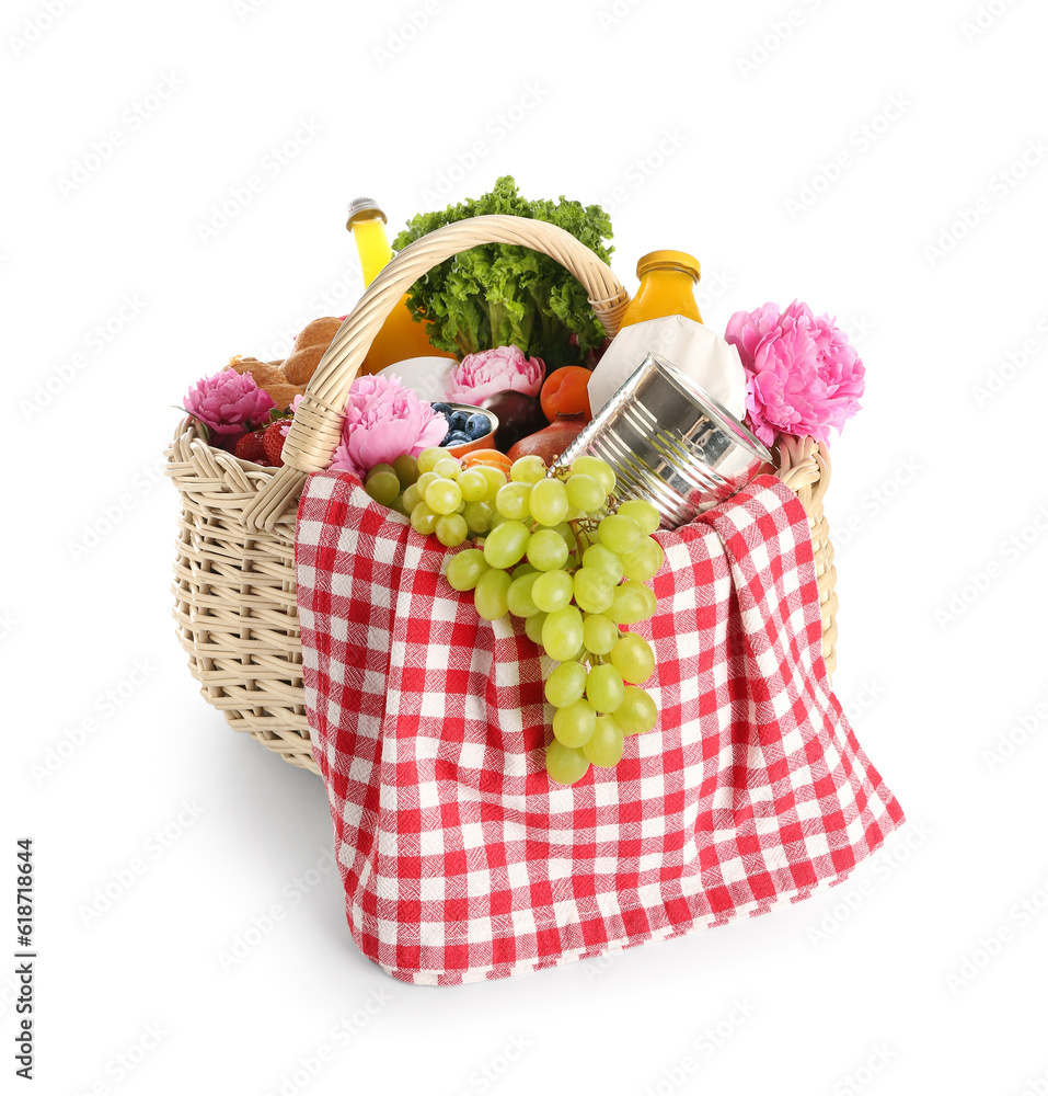 Wicker basket with tasty food for picnic, juice and peony flowers on white background