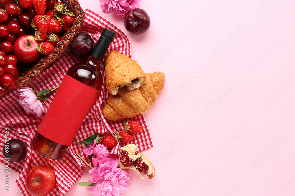 Composition with tasty food for picnic, bottle of wine and peony flowers on pink background