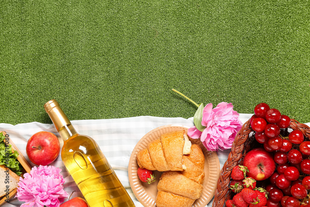 Composition with tasty food for picnic, wine and peony flowers on green background