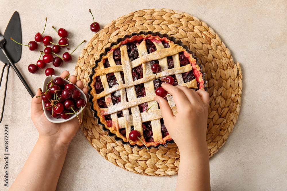 Woman decorating tasty cherry pie on white background