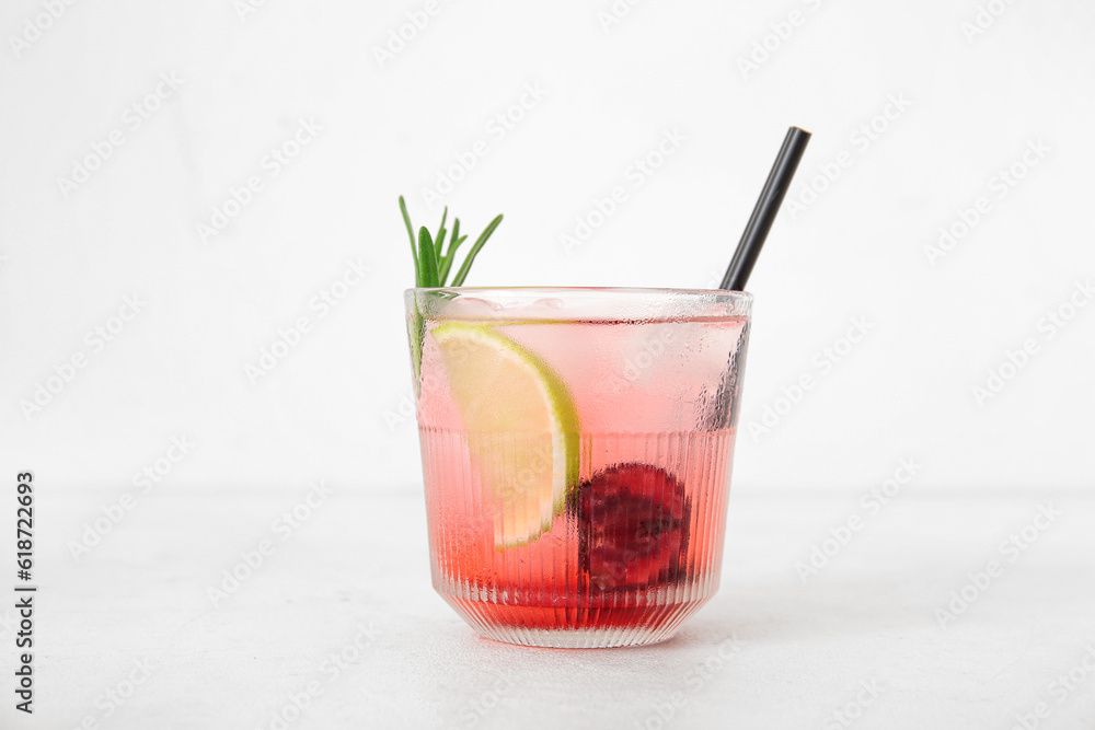 Glass of tasty cherry lemonade with lime and rosemary on white background