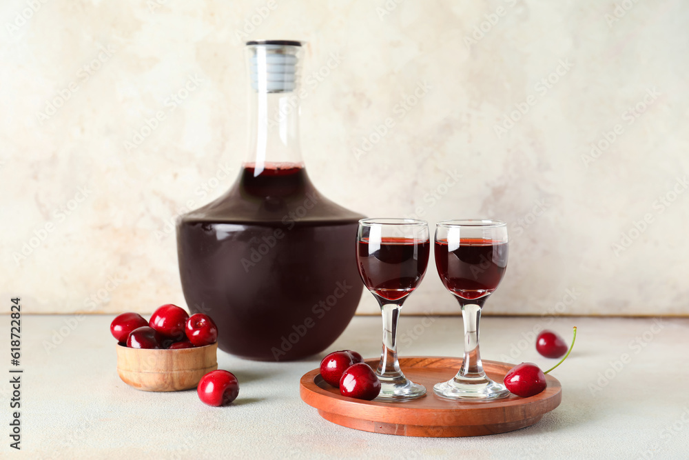 Glasses and bottle with sweet cherry liqueur on white background