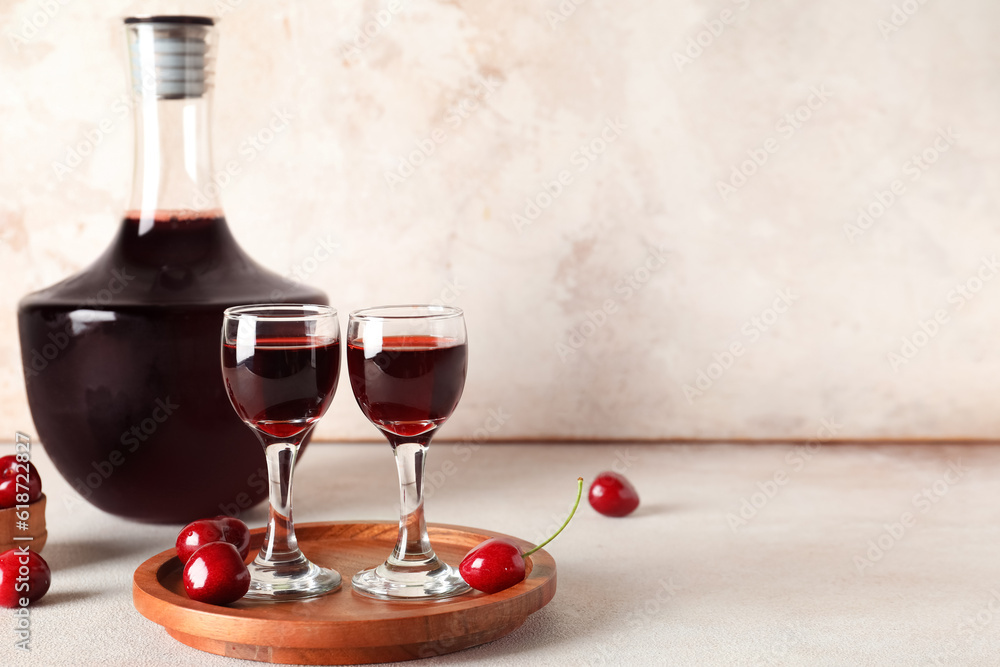 Glasses and bottle with sweet cherry liqueur on white background