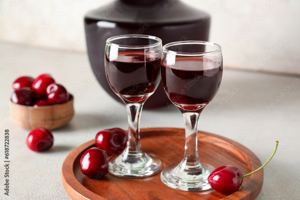 Glasses and bottle with sweet cherry liqueur on white background