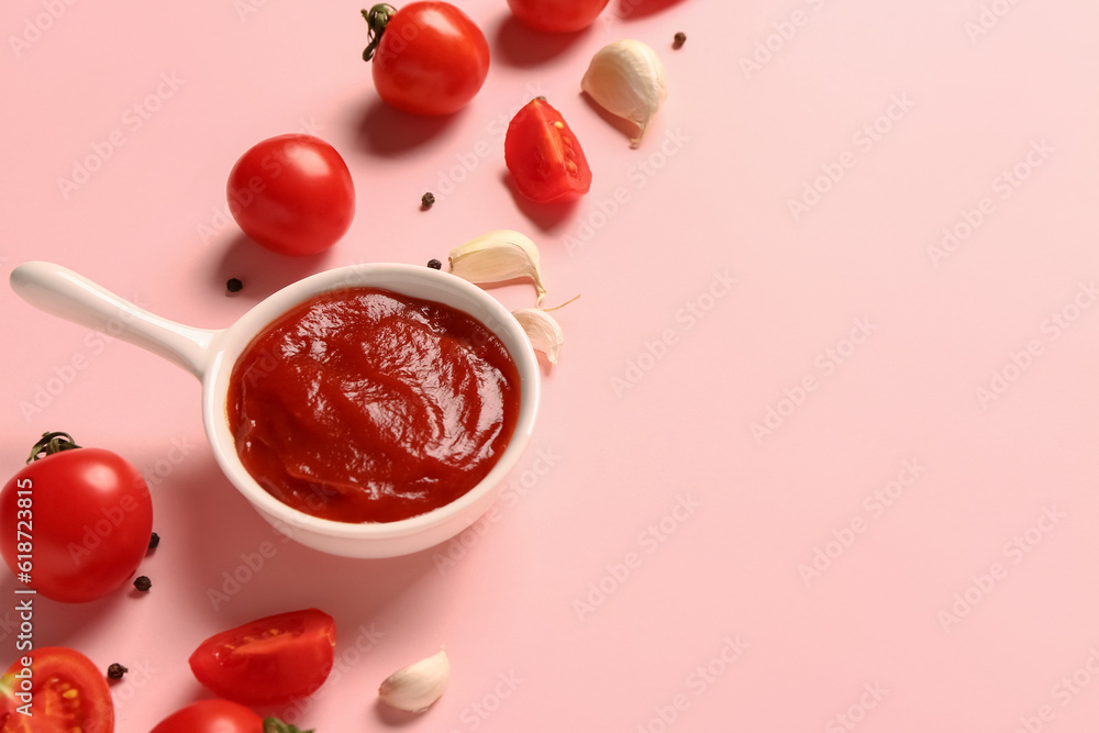 Bowl with tomato paste and fresh vegetables on pink background