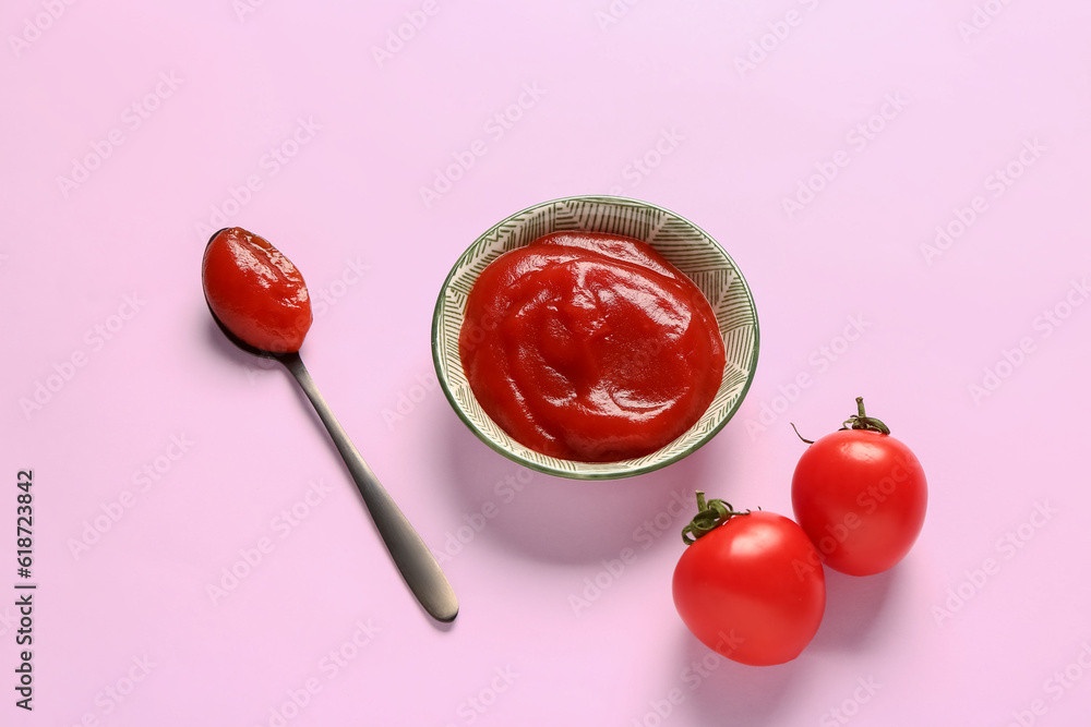 Bowl with tomato paste and fresh vegetables on lilac background