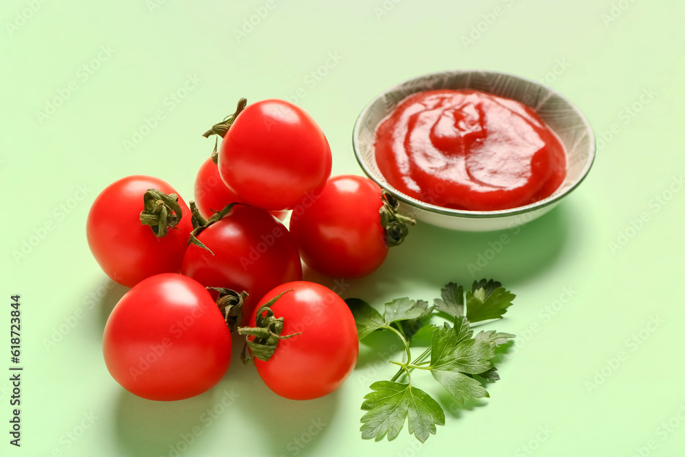 Bowl with tomato paste and fresh vegetables on green background