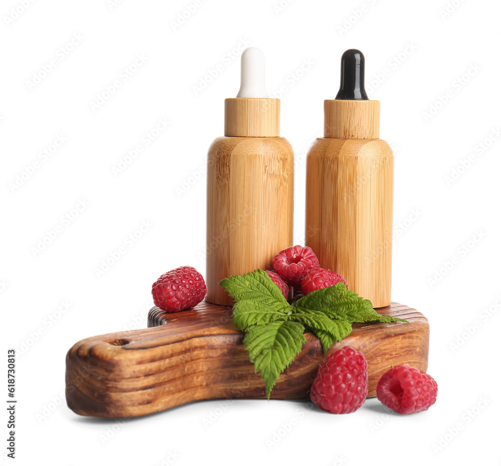 Wooden board with bottles of cosmetic raspberry oil on white background