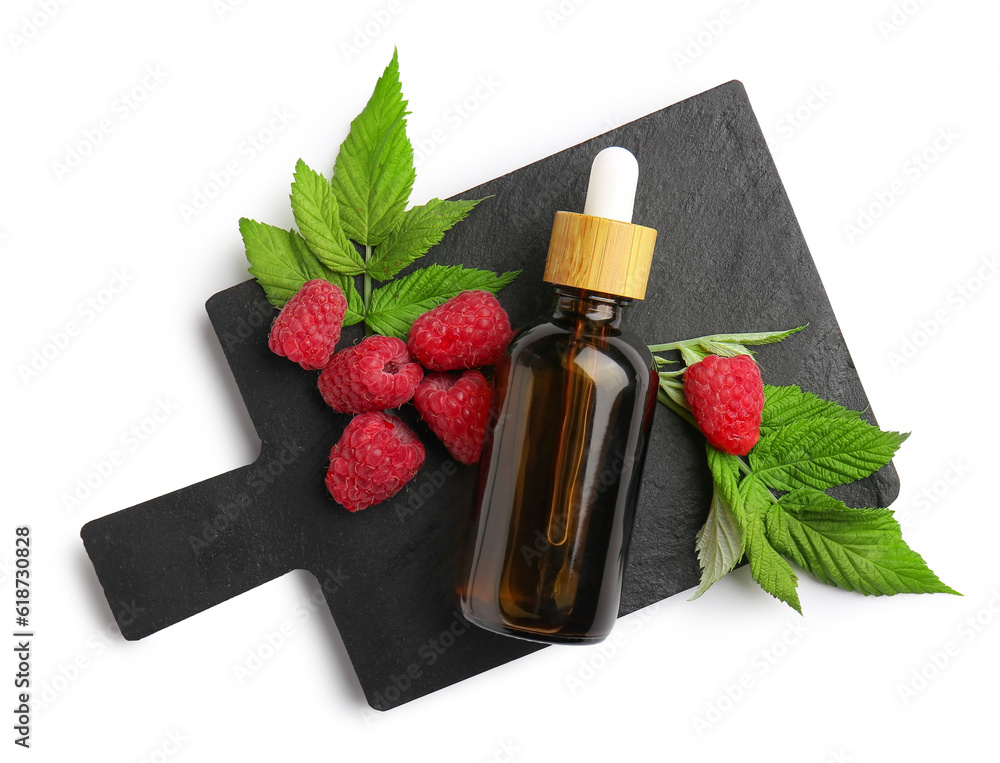 Board with bottle of cosmetic raspberry oil on white background