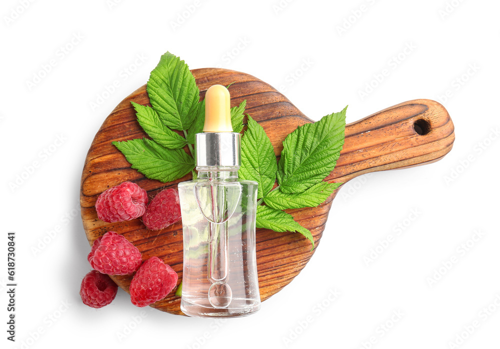 Wooden board with bottle of cosmetic raspberry oil on white background