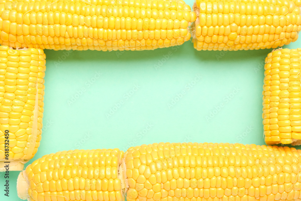 Frame made of fresh corn cobs on turquoise background