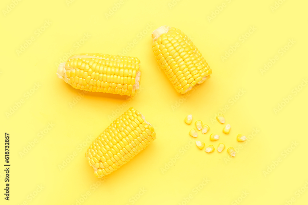 Cut fresh corn cobs and seeds on yellow background