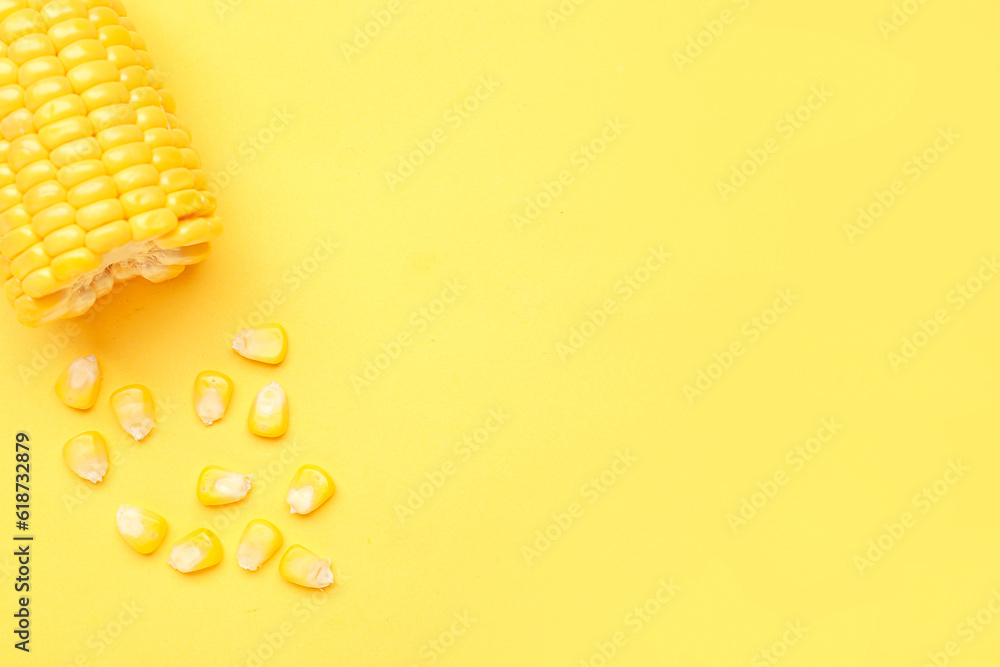 Cut fresh corn cob and seeds on yellow background