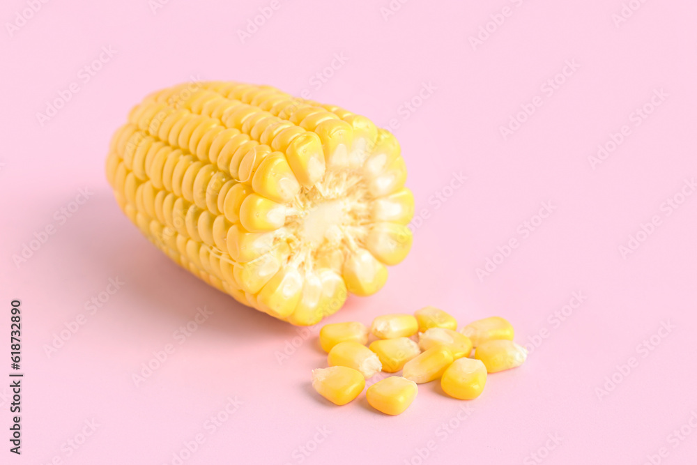 Cut fresh corn cob and seeds on pink background