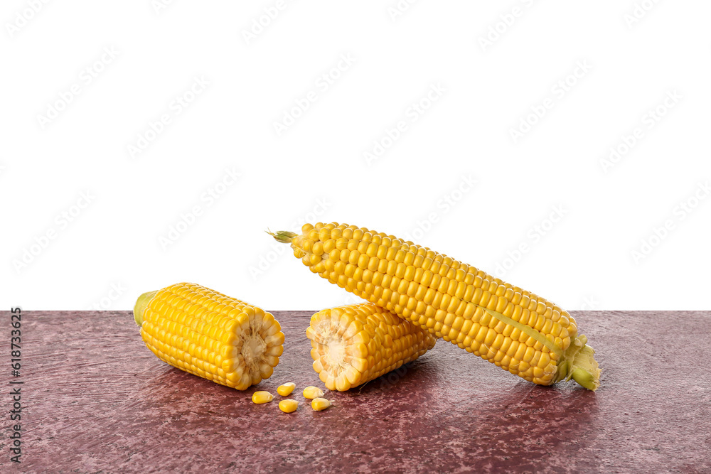 Fresh corn cobs and seeds on purple table against white background