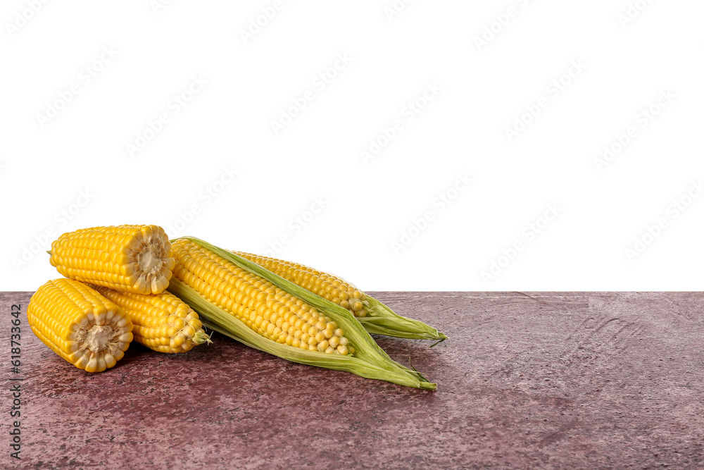 Fresh corn cobs on purple table against white background