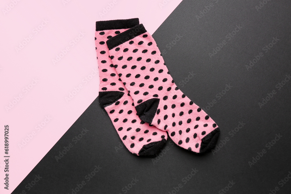 Pair of pink socks on color background