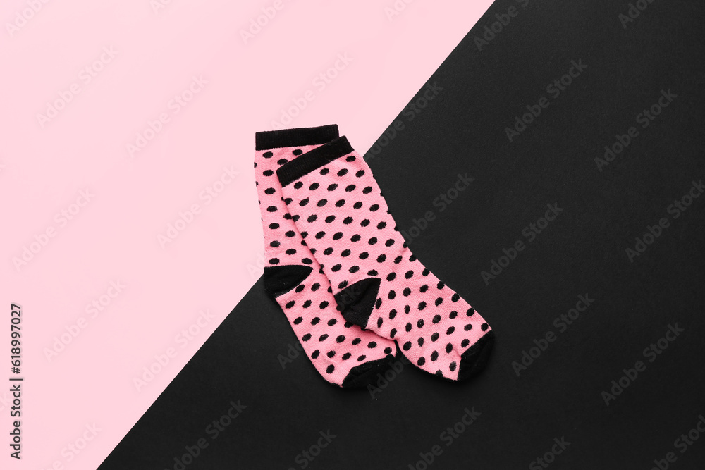 Pair of pink socks on color background