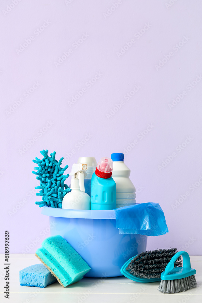 Bowl with different cleaning supplies on light wooden table