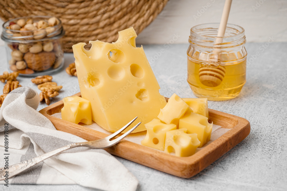 Board with pieces of Swiss cheese and honey on white table