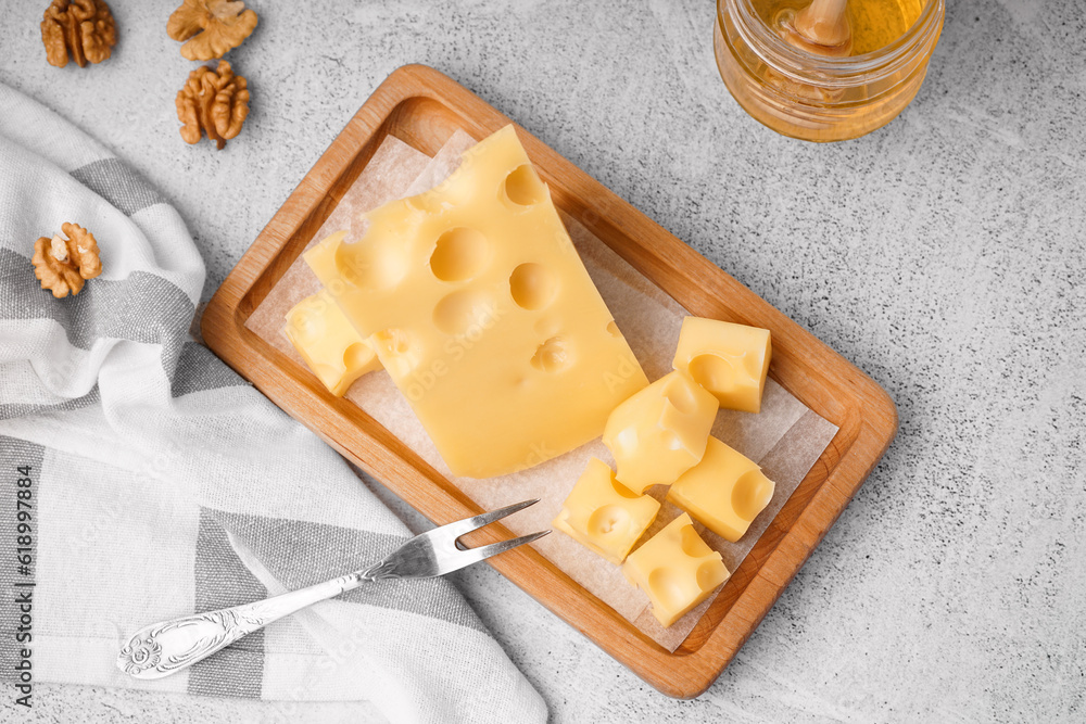 Board with pieces of Swiss cheese and honey on white table