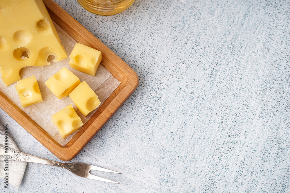 Board with pieces of Swiss cheese on white table