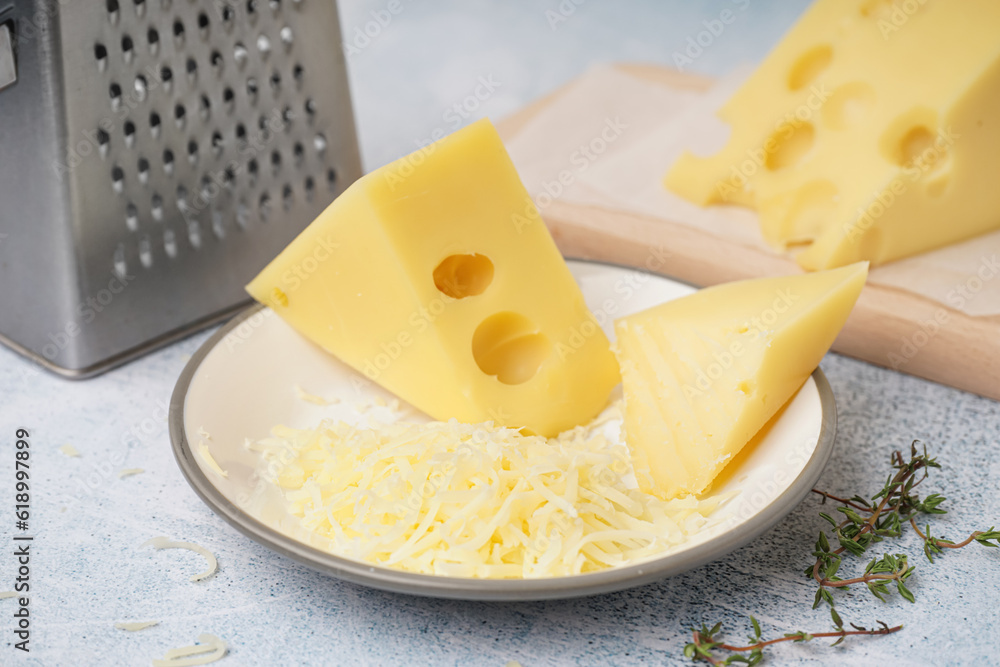 Plate and board with pieces of Swiss cheese on white table