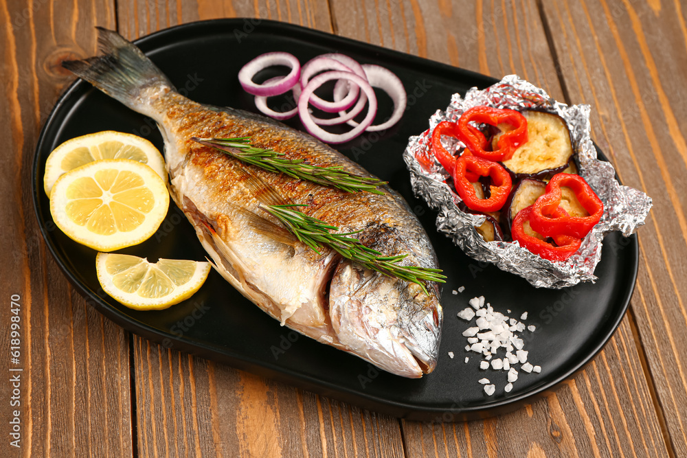 Tray with tasty grilled dorado fish on wooden background