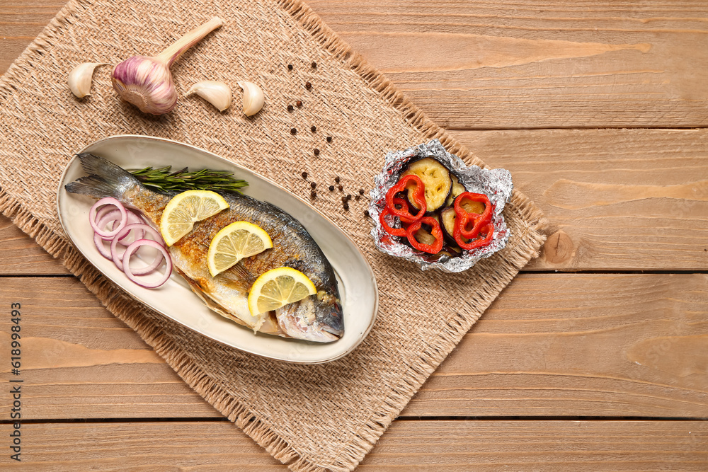 Plate with tasty grilled dorado fish on wooden background