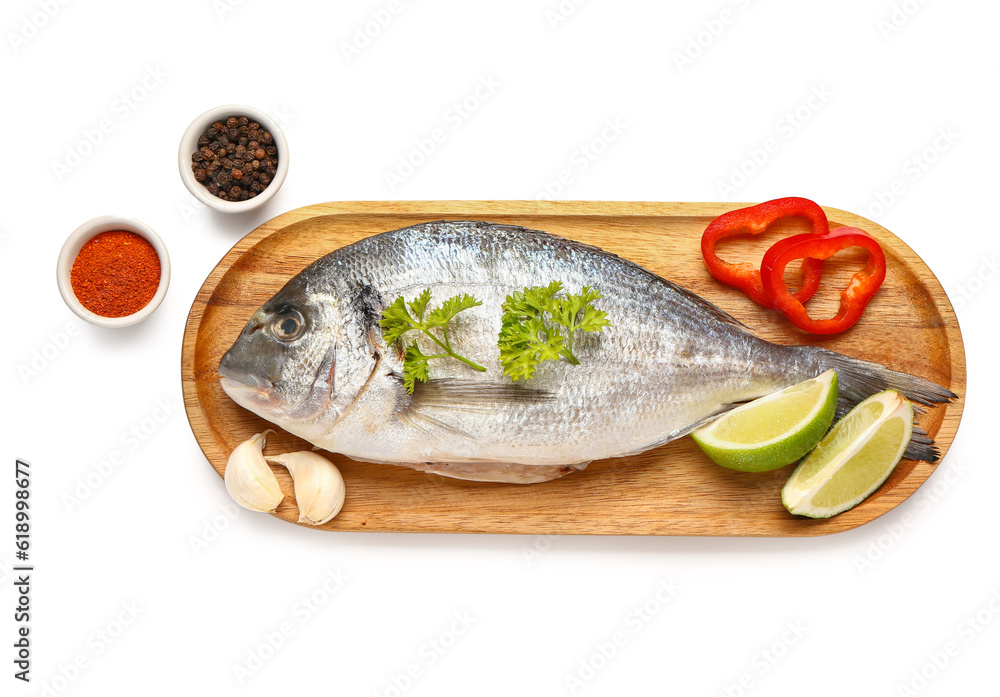 Wooden board of raw dorado fish with spices and lime on white background