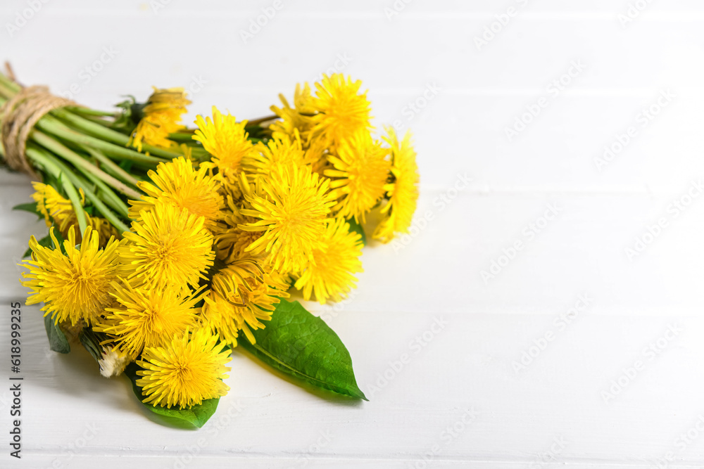 Bouquet of beautiful dandelion flowers on light wooden background