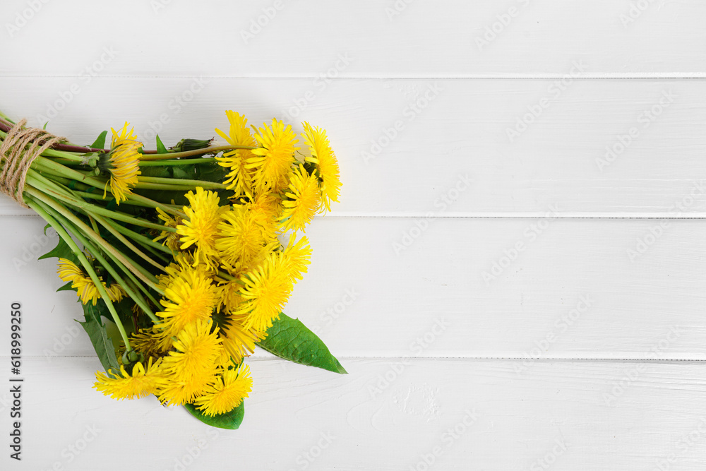 Bouquet of beautiful dandelion flowers on light wooden background