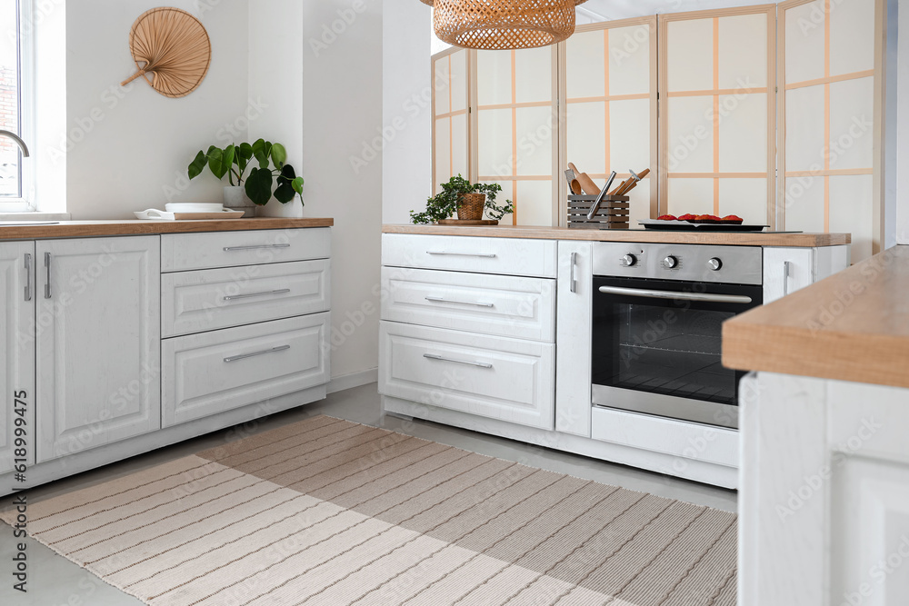 Interior of light kitchen with electric oven and white counters