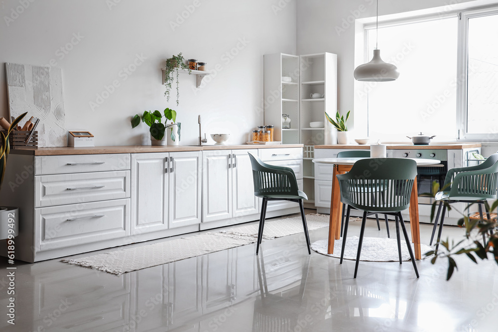 Interior of light kitchen with dining table and white counters